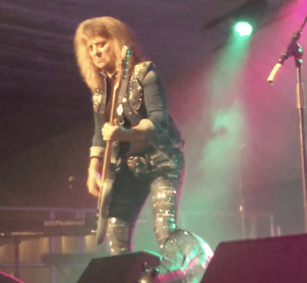Quatro plays on-stage with a guitar in-hand.